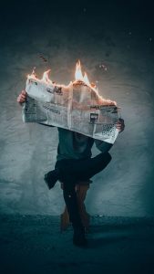 Man calmly reading a newspaper that is on fire
